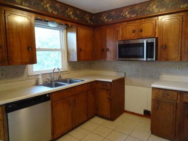 kitchen with backsplash, stainless steel appliances, light tile patterned flooring, and sink