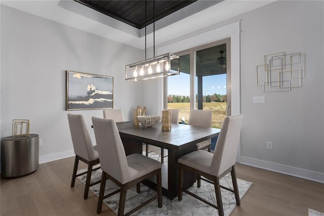 dining space with dark wood-type flooring, ceiling fan, and a tray ceiling