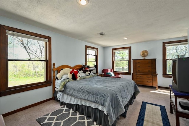 carpeted bedroom featuring multiple windows and a textured ceiling