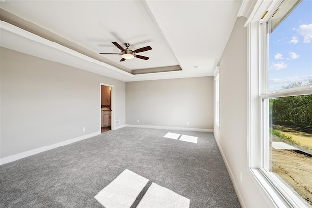 carpeted spare room with ceiling fan and a raised ceiling