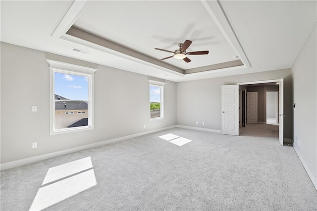 unfurnished bedroom with ceiling fan, a raised ceiling, and multiple windows