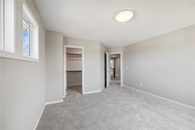 unfurnished bedroom with light colored carpet, a walk in closet, and a closet