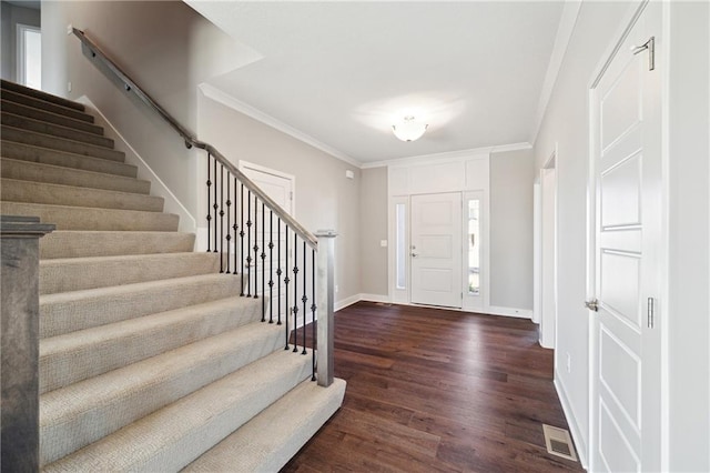 entrance foyer featuring a wealth of natural light, crown molding, and dark hardwood / wood-style flooring