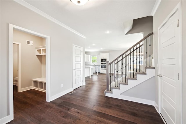 foyer entrance with crown molding and dark hardwood / wood-style floors