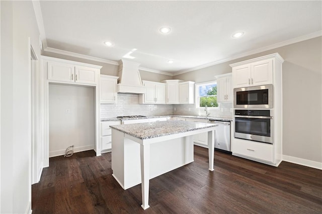 kitchen with premium range hood, white cabinets, appliances with stainless steel finishes, a kitchen island, and dark hardwood / wood-style flooring