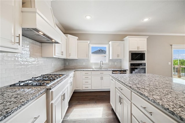 kitchen with tasteful backsplash, white cabinetry, premium range hood, and stainless steel appliances