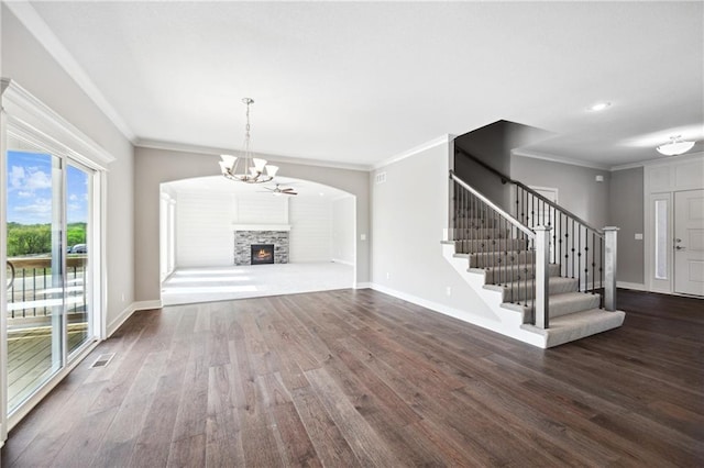 unfurnished living room with a fireplace, ornamental molding, dark hardwood / wood-style floors, and an inviting chandelier