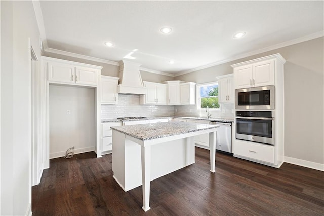 kitchen featuring custom exhaust hood, a center island, a kitchen breakfast bar, stainless steel appliances, and white cabinets