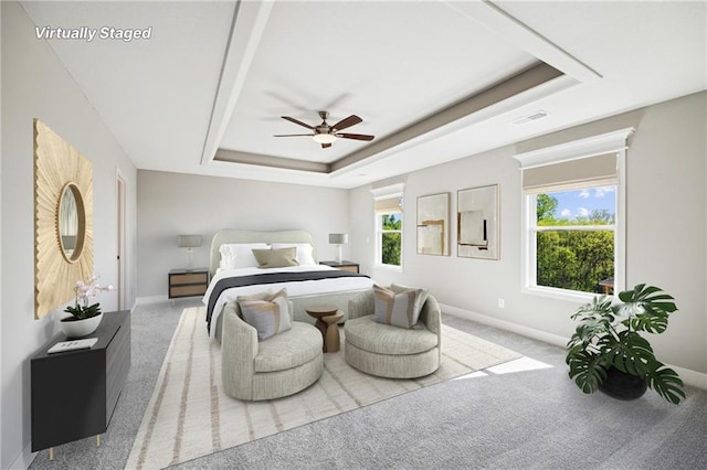 bedroom featuring a raised ceiling, light carpet, and ceiling fan