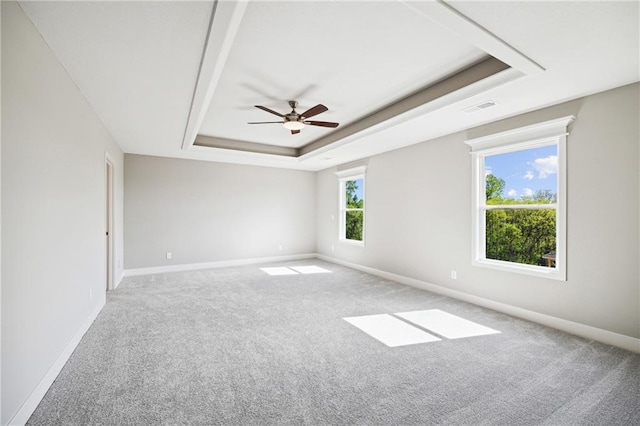 carpeted empty room featuring a raised ceiling and ceiling fan