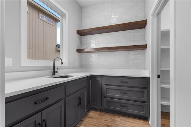 bar featuring sink, light hardwood / wood-style flooring, and backsplash