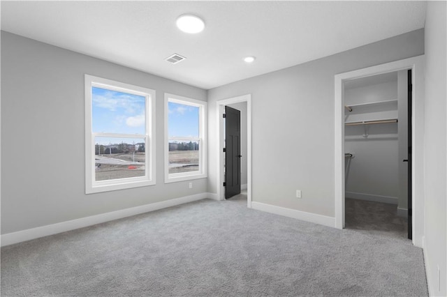 unfurnished bedroom featuring light colored carpet, a closet, and a walk in closet