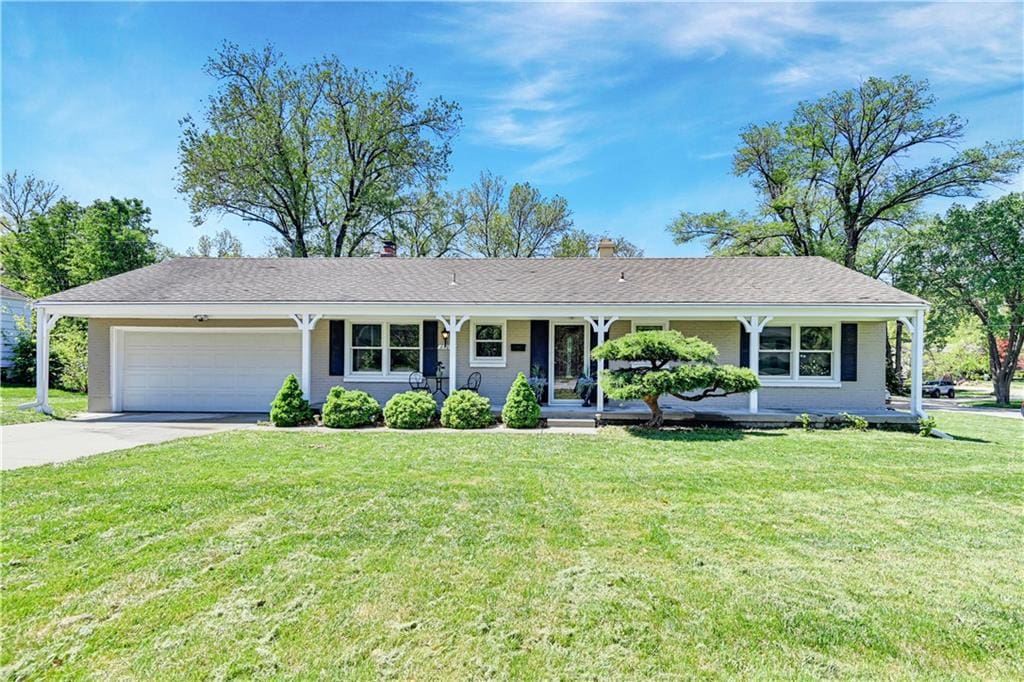 ranch-style house featuring a front yard, a garage, and covered porch