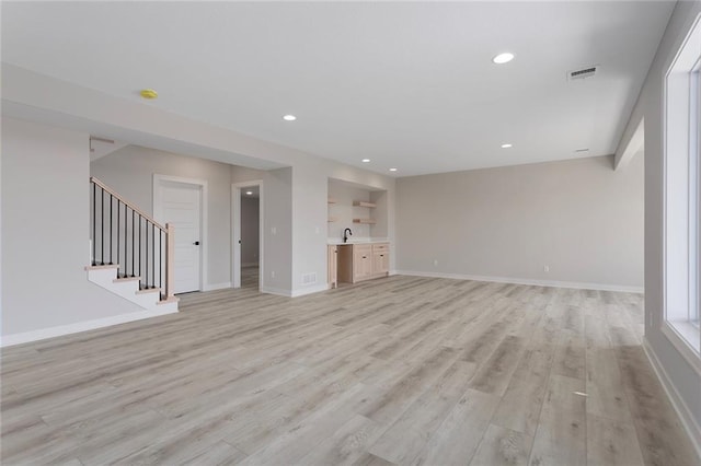 unfurnished living room with light wood finished floors, stairs, and baseboards