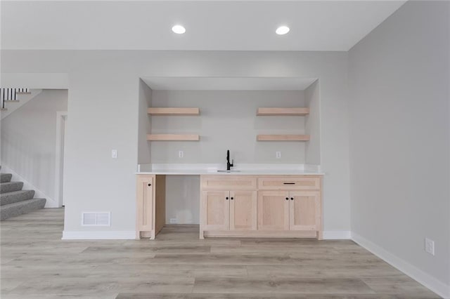 kitchen with a sink, visible vents, light wood-style floors, light brown cabinetry, and open shelves