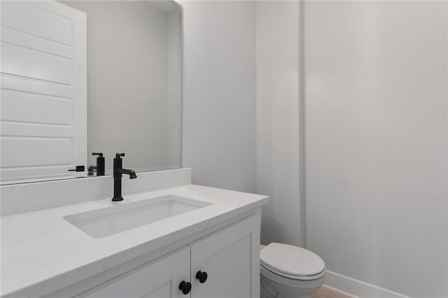 bathroom featuring baseboards, vanity, and toilet