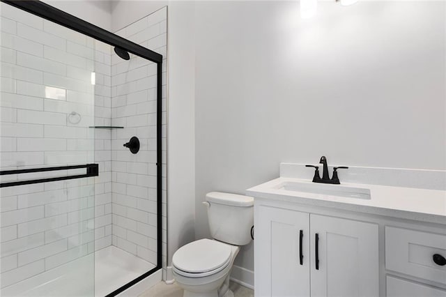 bathroom with vanity, a shower stall, toilet, and baseboards