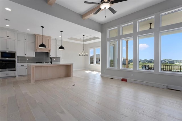 kitchen featuring open floor plan, appliances with stainless steel finishes, light wood finished floors, and backsplash