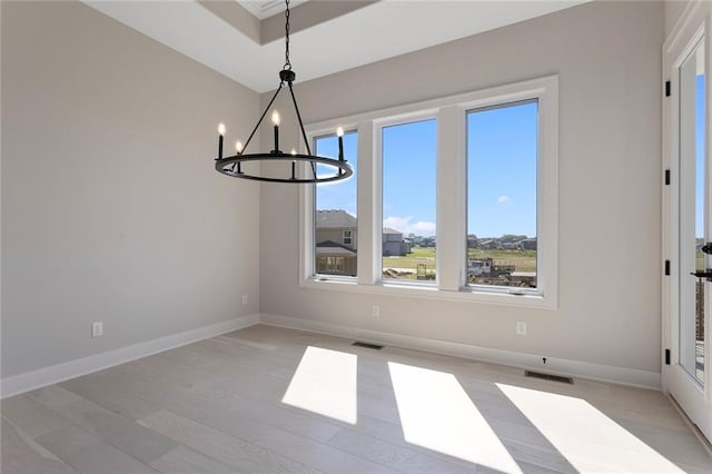 unfurnished dining area with a chandelier, visible vents, light wood-style floors, and baseboards