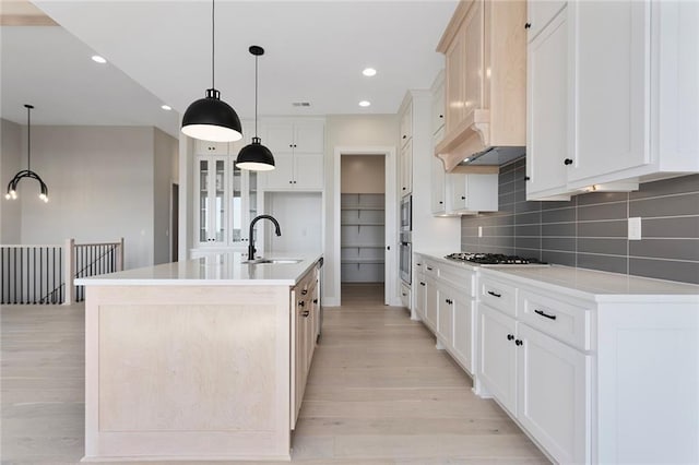 kitchen with light wood-style floors, tasteful backsplash, gas cooktop, and a sink