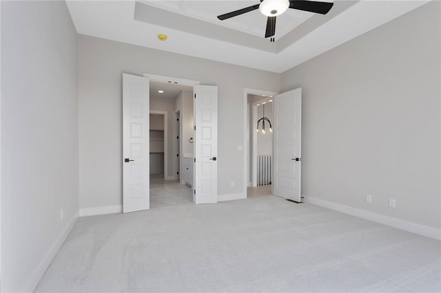 unfurnished bedroom featuring light carpet, baseboards, and a tray ceiling