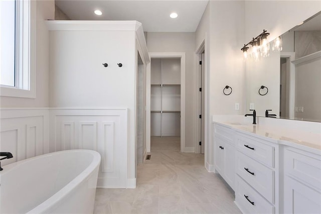 bathroom with a walk in closet, a freestanding bath, vanity, and recessed lighting