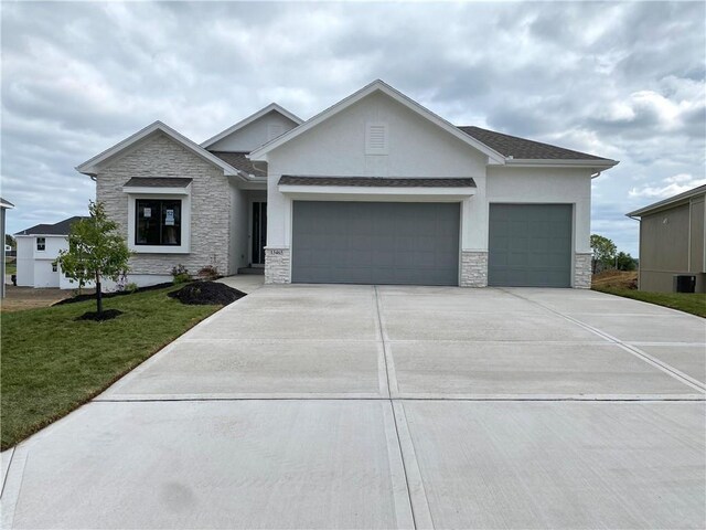 view of front of home featuring concrete driveway, stone siding, stucco siding, an attached garage, and a front yard