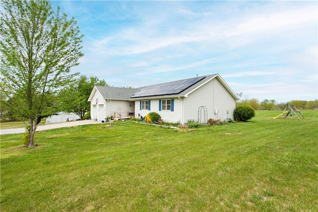 single story home featuring a playground, a front lawn, solar panels, and a garage