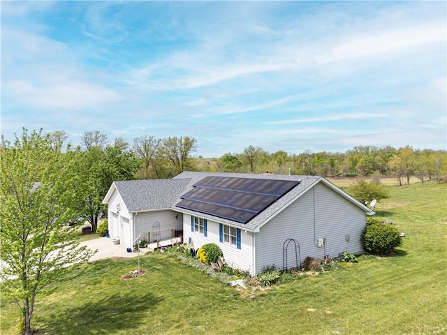 exterior space featuring a front yard, a garage, and solar panels