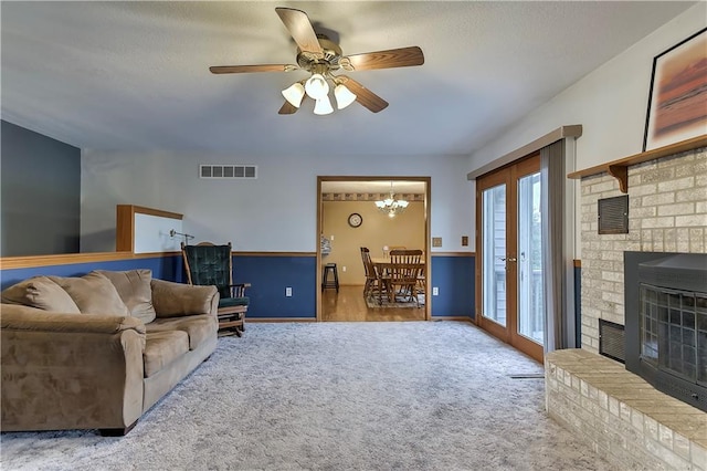 sitting room featuring ceiling fan with notable chandelier, light hardwood / wood-style floors, and a brick fireplace