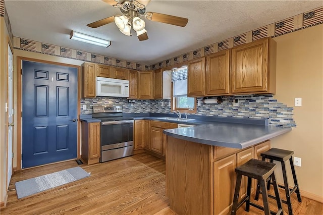 kitchen featuring tasteful backsplash, kitchen peninsula, light hardwood / wood-style flooring, stainless steel electric stove, and ceiling fan