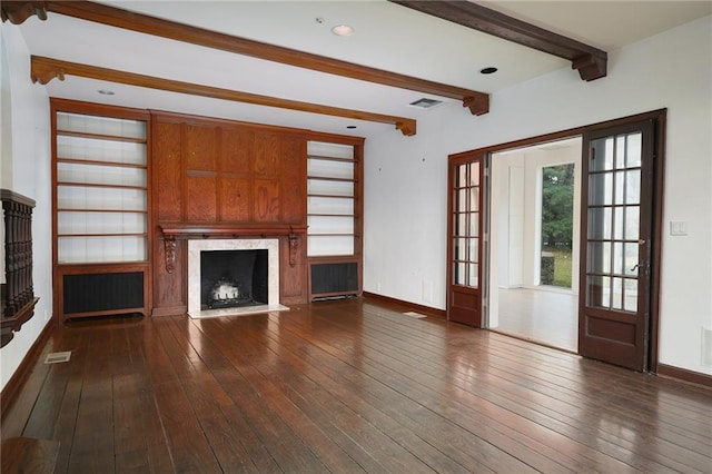 unfurnished living room featuring beam ceiling, radiator heating unit, dark hardwood / wood-style floors, a fireplace, and built in shelves