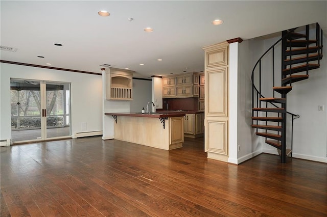 kitchen featuring cream cabinets, dark wood-type flooring, a kitchen bar, and baseboard heating