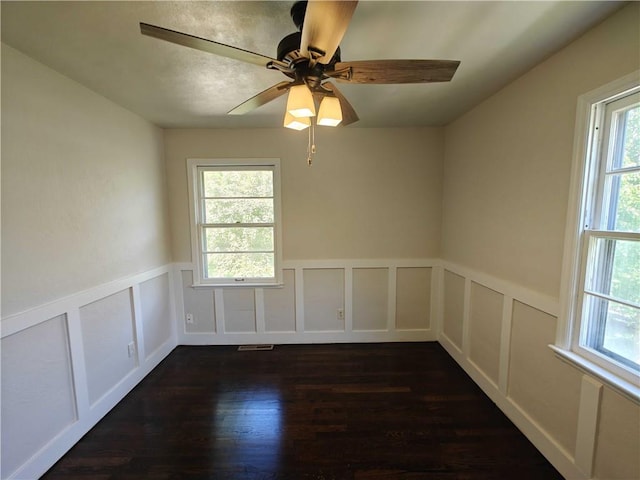 unfurnished room with ceiling fan, a wealth of natural light, and dark wood-type flooring