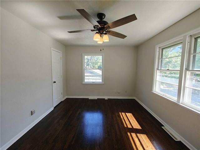 spare room featuring dark wood-type flooring and plenty of natural light