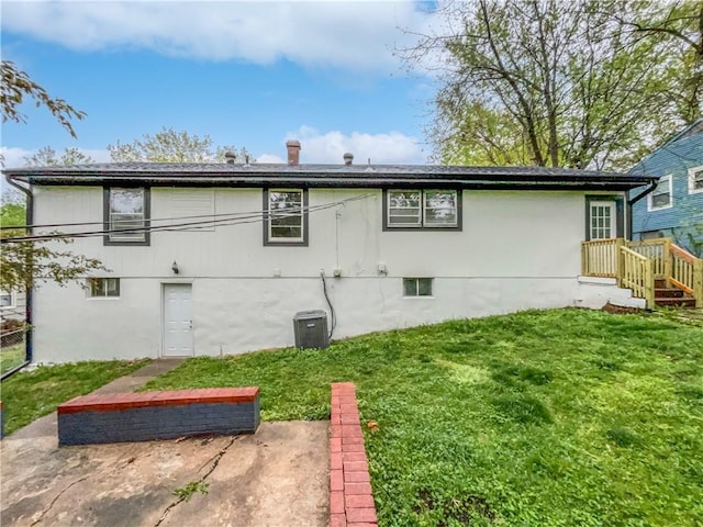 rear view of house with central air condition unit, a lawn, and a patio area