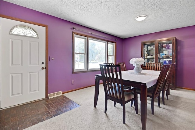 carpeted dining area featuring a textured ceiling