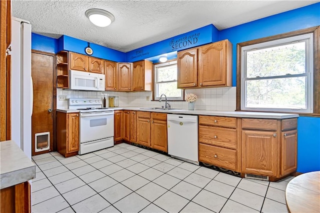 kitchen featuring sink, white appliances, tasteful backsplash, and light tile flooring