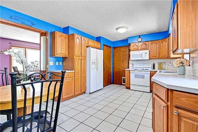 kitchen with light tile floors, tasteful backsplash, white appliances, and sink