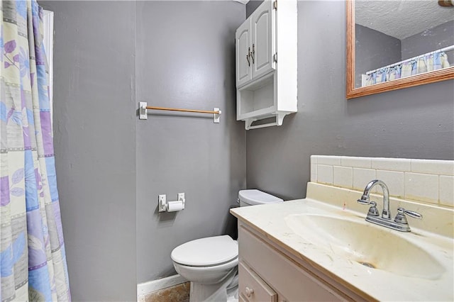 bathroom with backsplash, a textured ceiling, oversized vanity, and toilet