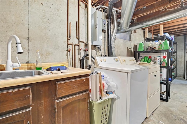 clothes washing area with sink, water heater, and washing machine and clothes dryer