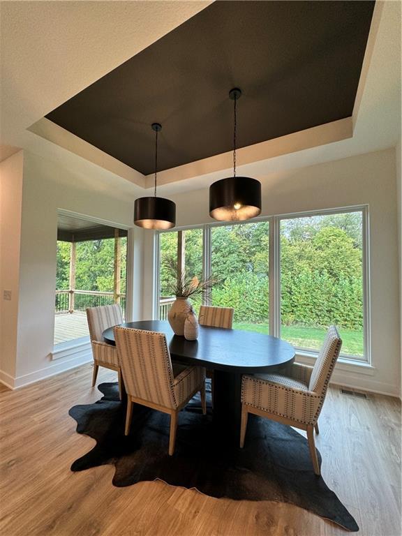 dining room featuring a raised ceiling and light wood-type flooring