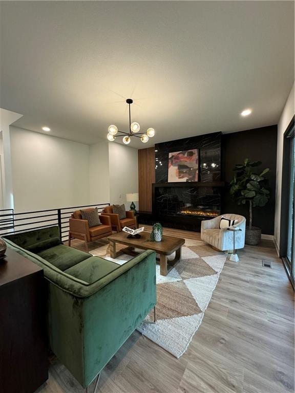 living room with a chandelier, a fireplace, and light hardwood / wood-style floors