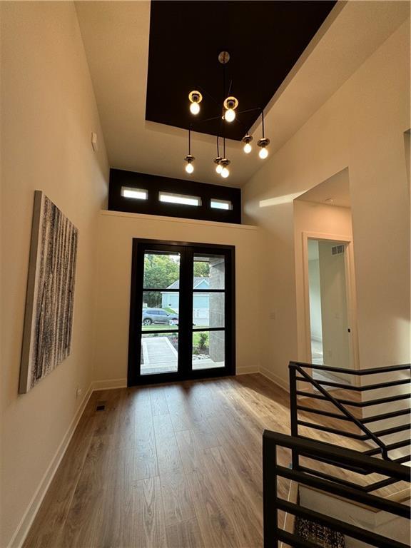 entryway with wood-type flooring, a towering ceiling, and a tray ceiling