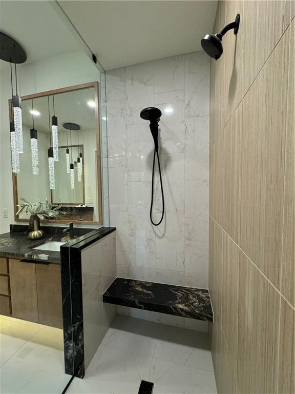 bathroom featuring vanity, walk in shower, and tile walls