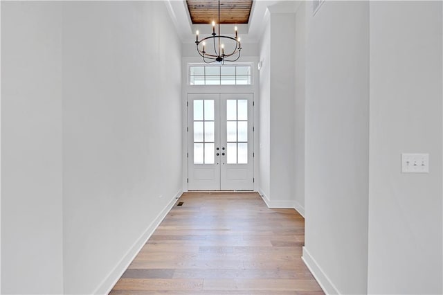 entryway featuring crown molding, french doors, a chandelier, and light hardwood / wood-style flooring