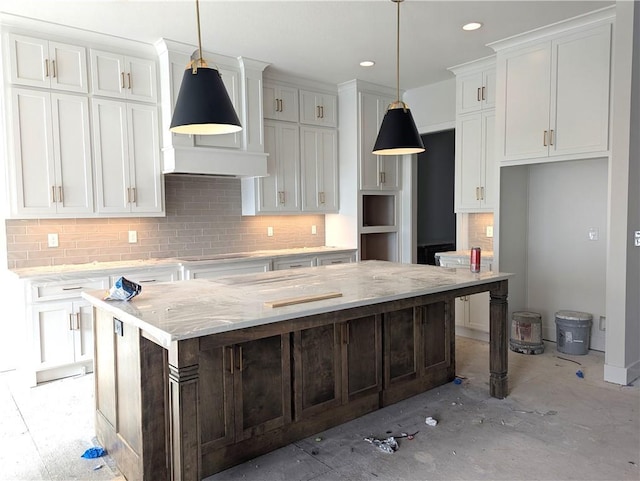 kitchen featuring a large island, light stone counters, tasteful backsplash, white cabinets, and decorative light fixtures