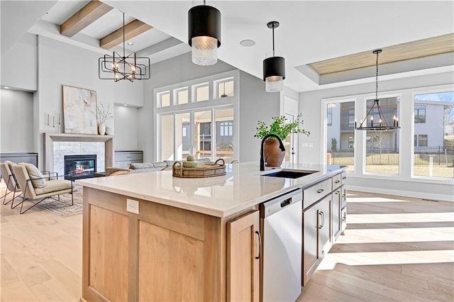 kitchen featuring stainless steel dishwasher, sink, an island with sink, and pendant lighting