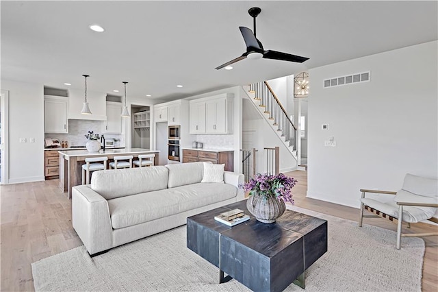 living room with sink, ceiling fan, and light hardwood / wood-style flooring