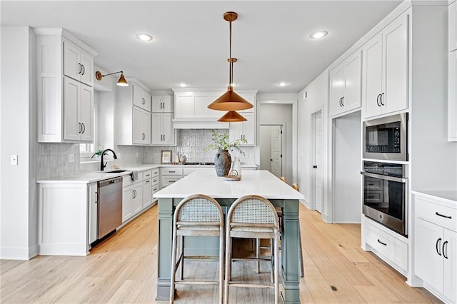 kitchen with white cabinetry, decorative light fixtures, stainless steel appliances, and a center island